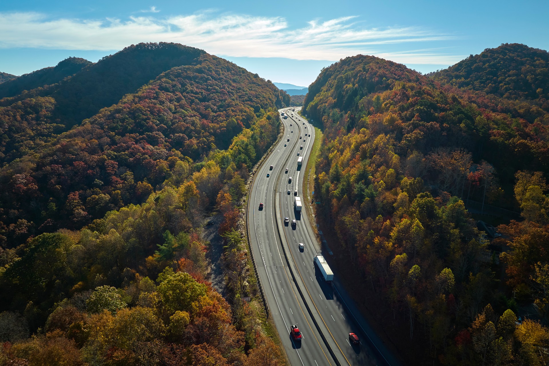Vista desde arriba de la autopista I-40 en Carolina del Norte en dirección a Asheville a través de las montañas Apalaches en la temporada dorada de otoño con camiones y automóviles de conducción rápida. Concepto de transporte interestatal
